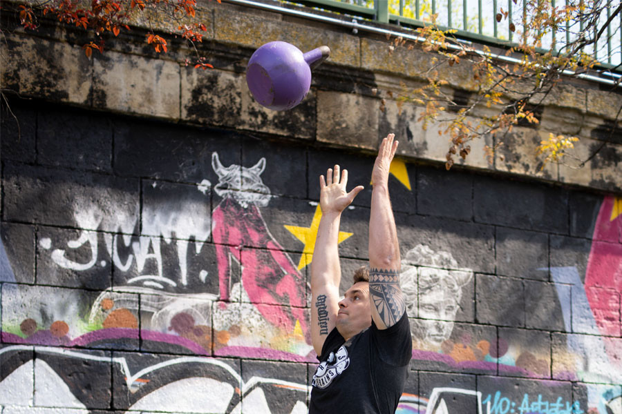 Philipp wirft einen Kettlebell in die Luft.